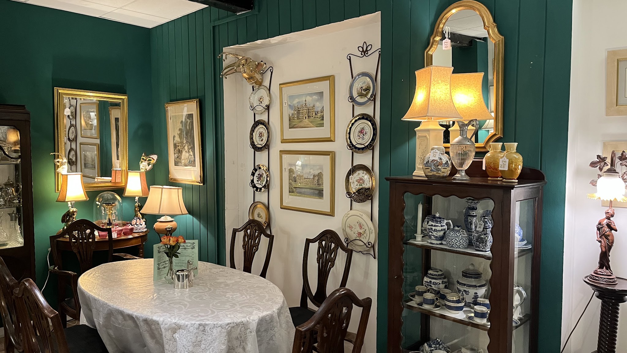 Antique mirrors, framed plates and lamplight inside the tea room